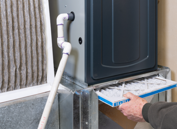Replacing a dirty furnace filter in a home by a technician.